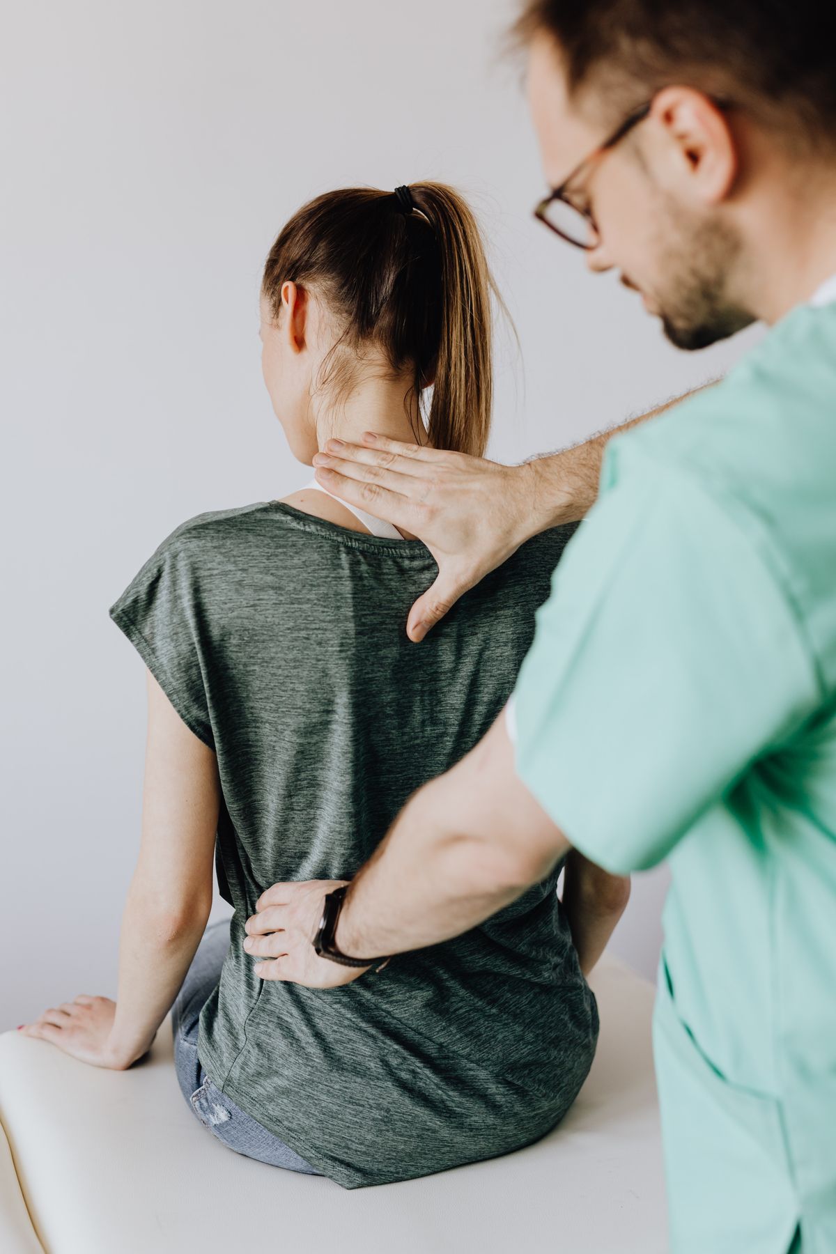 Ein Arzt untersucht den Rücken einer Patientin